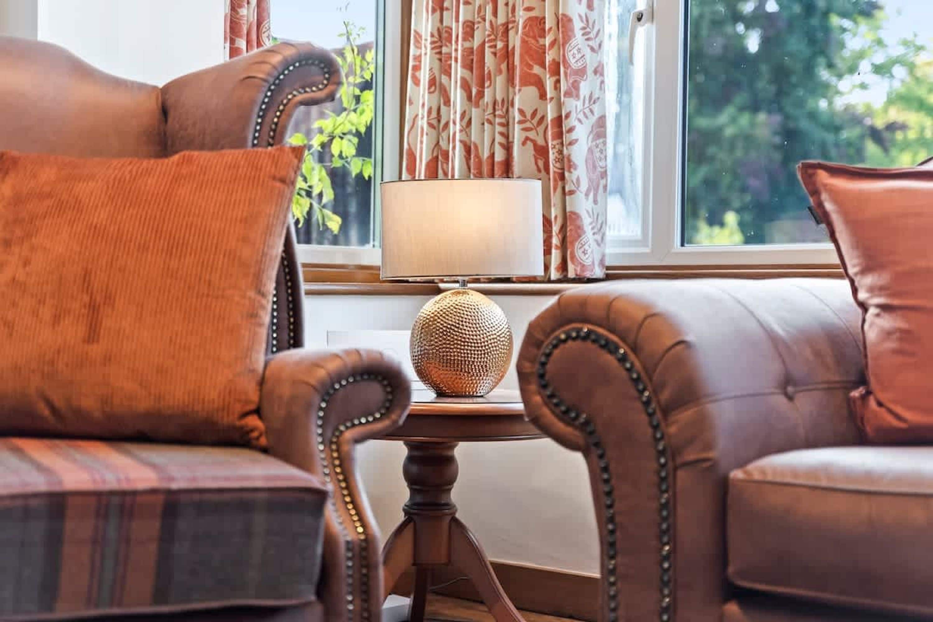 A room with a sofa, a table with a lamp, and a view through a window.
