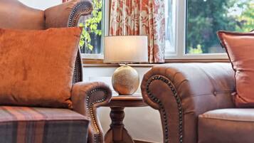 A room with a sofa, a table with a lamp, and a view through a window.