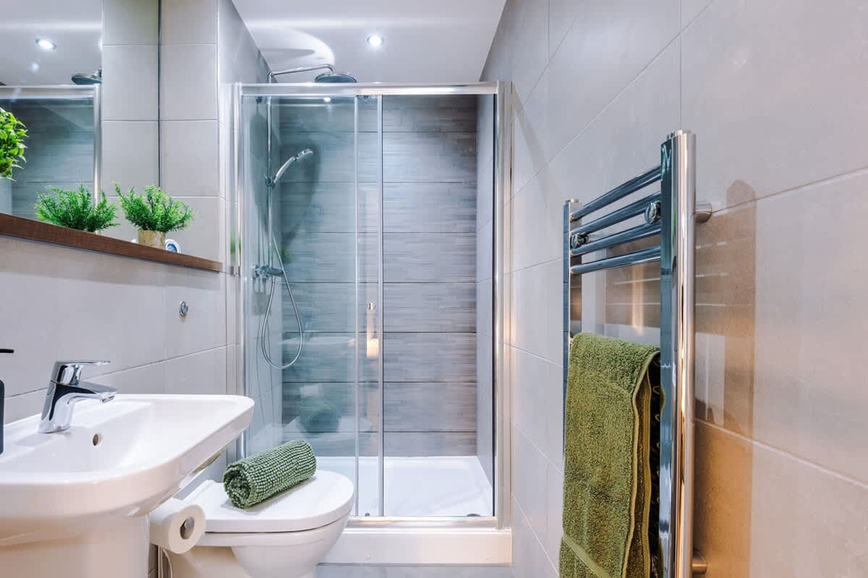 A modern bathroom with a glass shower enclosure, a sink, and a toilet.