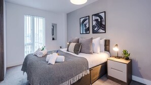 Ein modernes Schlafzimmer mit Bett, Nachttisch, Lampe und Kunstwerk.