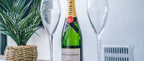 A bottle of Moët & Chandon champagne and two glasses on a table with a woven basket and a plant.