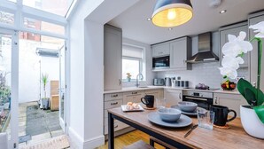 Une cuisine moderne avec un coin repas, de grandes fenêtres et une vue sur le jardin.