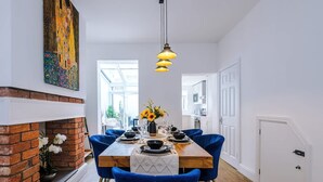 Un coin repas agrémenté d’une cheminée en briques, de chaises bleues, d’une table en bois et d’un luminaire suspendu.