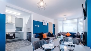 A modern kitchen with white cabinets, a built-in oven, and a dining area with a table set for two. - Spacious 3-bed Ideal for Long-term Business (Manchester)