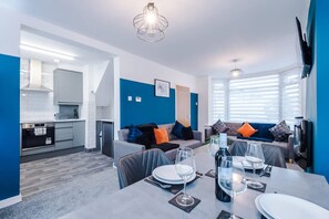 A modern kitchen with white cabinets, a built-in oven, and a dining area with a table set for two. - Spacious 3-bed Ideal for Long-term Business (Manchester)