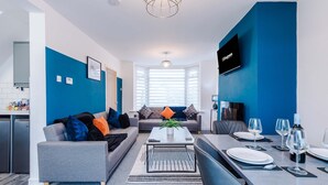 A modern living room with a sofa, coffee table, and dining area. - Spacious 3-bed Ideal for Long-term Business (Manchester)