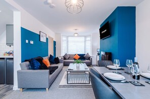 A modern living room with a sofa, coffee table, and dining area. - Spacious 3-bed Ideal for Long-term Business (Manchester)