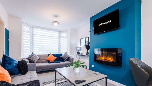 A modern living room with a sofa, coffee table, and a fireplace. - Spacious 3-bed Ideal for Long-term Business (Manchester)