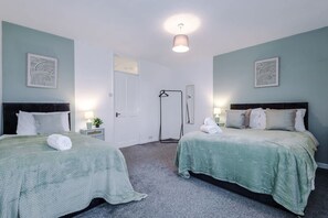 A hotel room with two beds, a wardrobe, a mirror, a hanging rack, and a door. - Spacious Home Ideal for Contractors Sleeps 7 (Manchester)