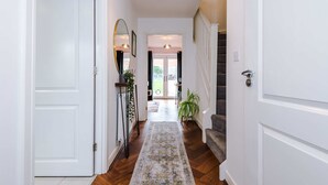 Un pasillo con un tapete estampado, una escalera y una puerta que da a un espacio exterior.