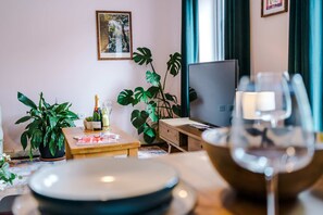 Une pièce avec une table en bois, une plante en pot, un téléviseur et un verre de vin.