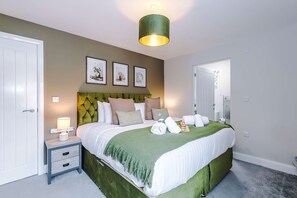 A bedroom with a bed, bedside table, wall art, and a green headboard. - Modern City Centre 3 Bed Apartment Great for Couples (Chester)