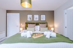 A neatly arranged bedroom with a bed, pillows, a bedside table, a lamp, and a green rug. - Modern City Centre 3 Bed Apartment Great for Couples (Chester)