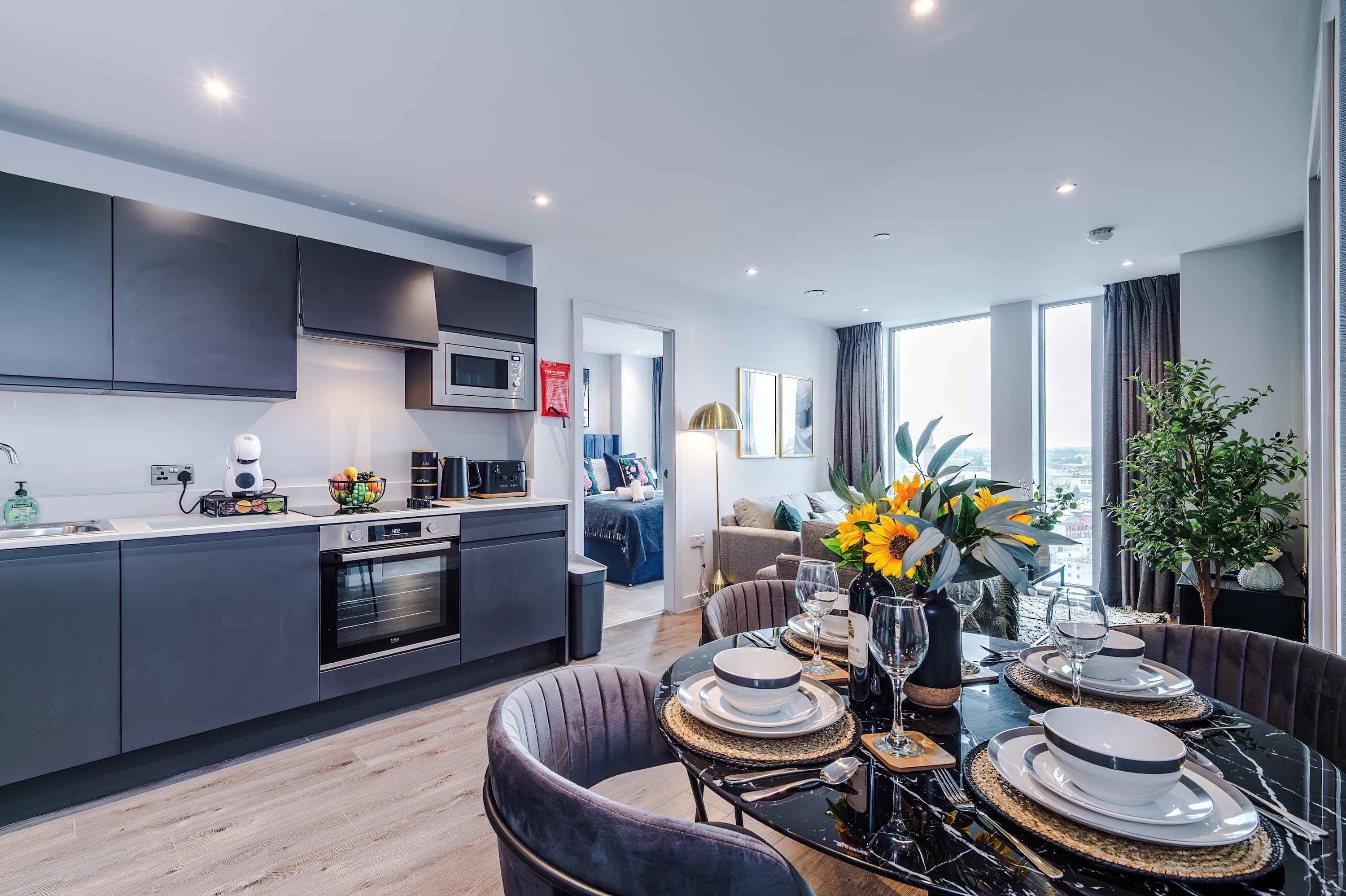 A modern kitchen with dark cabinets, a microwave, and a dining area with a table set for four.