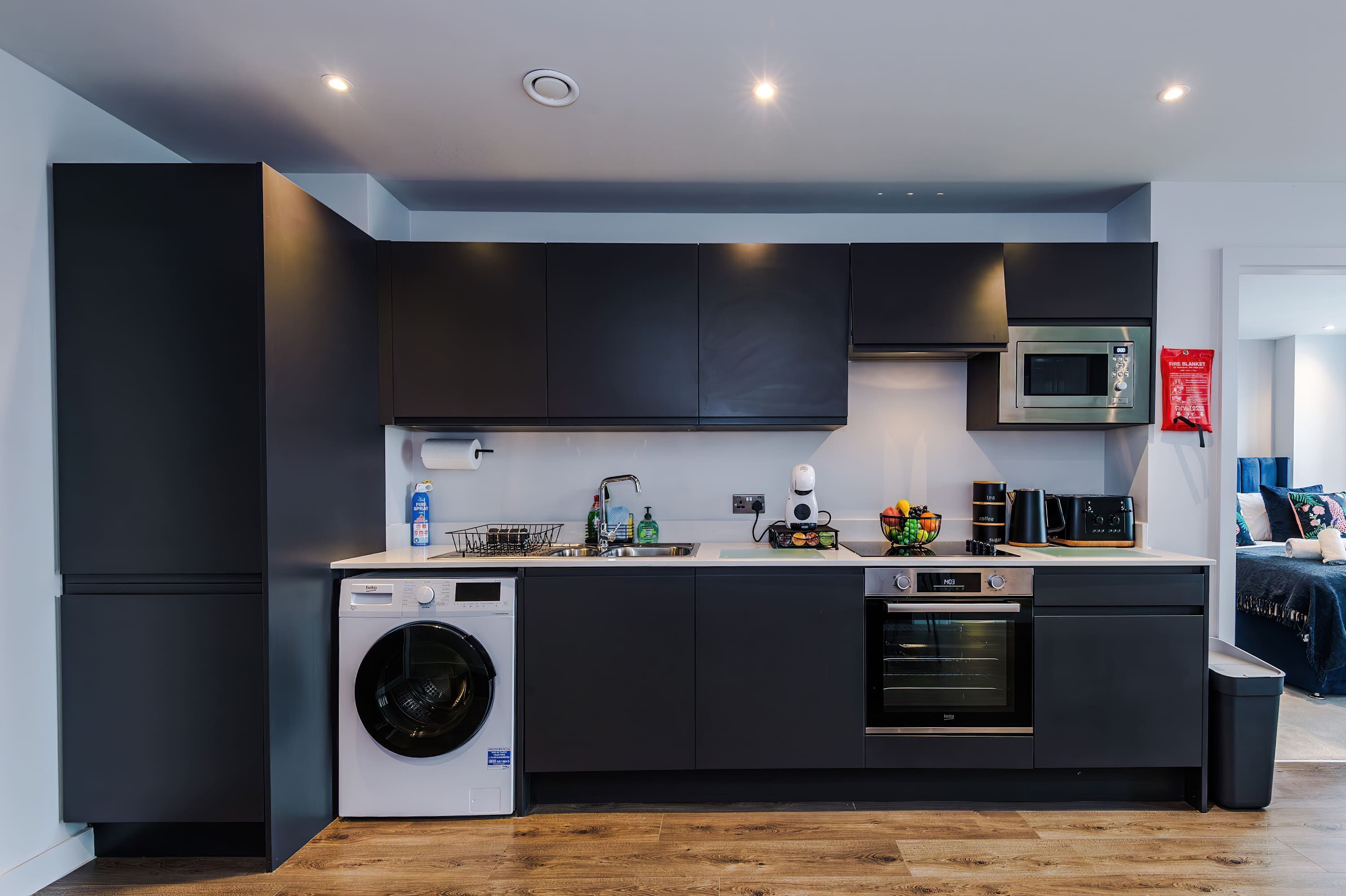 Une cuisine compacte équipée d’un lave-linge, d’un four à micro-ondes et d’un four traditionnel.