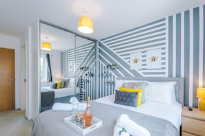 A modern hotel room with a bed, bedside table, and a large mirror. - Perfect Riverside Home in Manchester Free Parking (Salford)