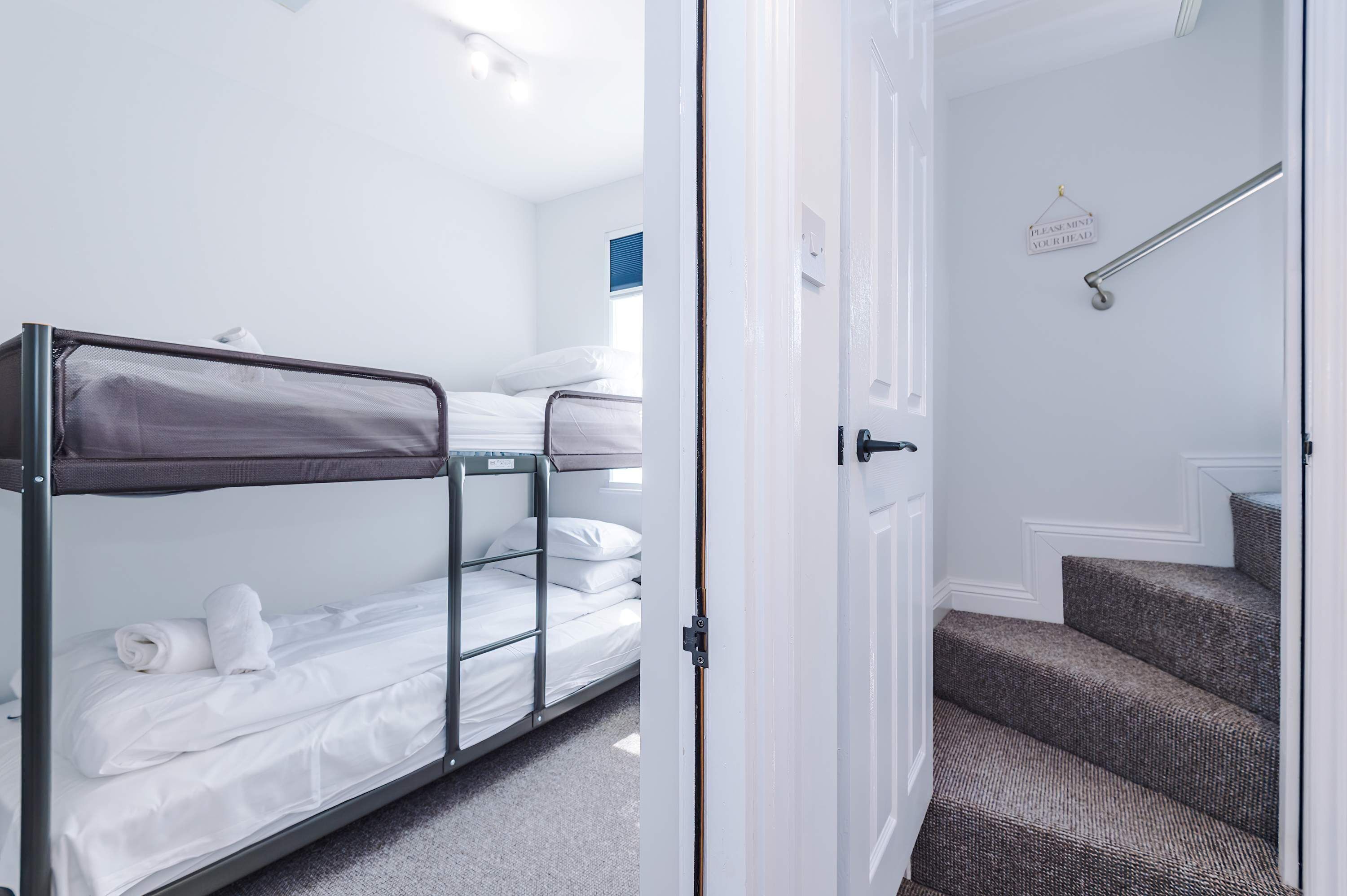 Een hotelkamer met stapelbedden, een trap en een bord op de muur.