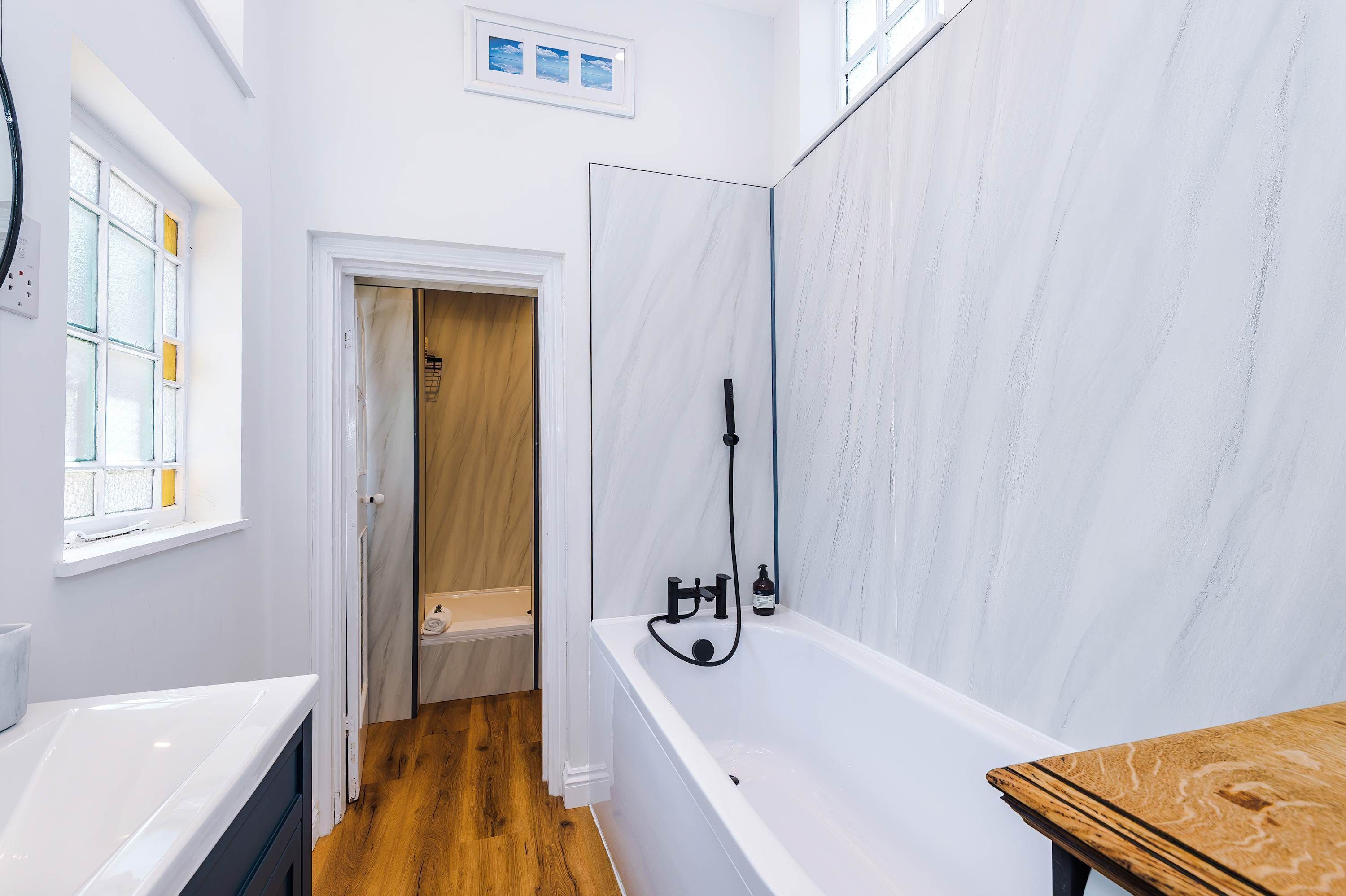 A bathroom with a bathtub, a shower, and a wooden floor.