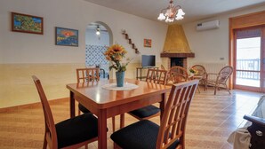 Een eethoek met een houten tafel, stoelen, een vaas met bloemen, een televisie en een open haard.