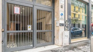 Ein Gebäudeeingang mit vergitterten Türen, einem Schild, das eine Garage kennzeichnet, und einem durch das Fenster sichtbaren Auto.