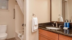 Une salle de bain équipée de toilettes, d’une douche, d’un lavabo et d’un miroir.