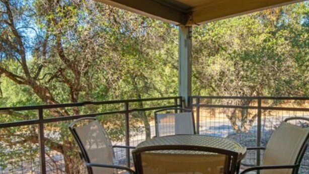 Un espace extérieur abrité, avec des rampes en métal, des chaises et une table.