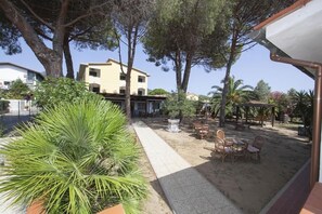 Une cour avec du mobilier d’extérieur, un chemin et un bâtiment en arrière-plan.