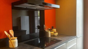 Une cuisine moderne avec une hotte noire, des armoires blanches et un plan de travail gris.