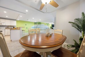 A dining area with a wooden table and chairs, a ceiling fan, and a kitchen in the background. - Luxury 4-bedroom oceanblock retreat on 138th Street offering plenty of space and a pool (Ocean City)