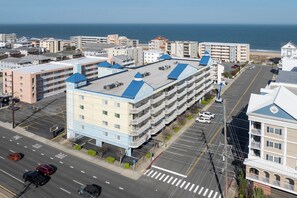 A multi-story hotel with a parking lot, a street view, and a beach in the background. - Luxury 4-bedroom oceanblock retreat on 138th Street offering plenty of space and a pool (Ocean City)