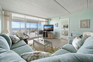 Una sala de estar con sofá, mesa de centro, televisor y balcón con vistas.