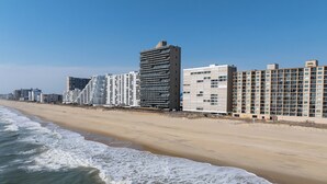 Um hotel à beira-mar com vários edifícios altos, uma praia arenosa e ondas se aproximando da costa.