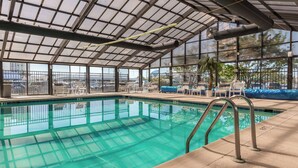 Uma grande piscina coberta com águas azuis cristalinas, rodeada por espreguiçadeiras e uma cobertura.
