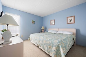 A bedroom with a bed, a desk, a lamp, and two framed pictures on the wall. - Walk Right Out to the Beach or Enjoy Stunning Bay Views (Ocean City)