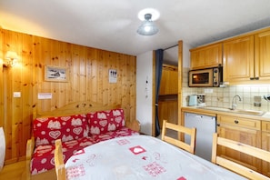 Une chambre avec un lit en bois, une petite kitchenette équipée d’un four à micro-ondes et un meuble en bois.