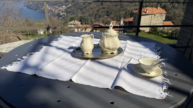 Ein Tisch mit weißer Tischdecke und Tee-Service, mit Blick auf eine Berglandschaft.