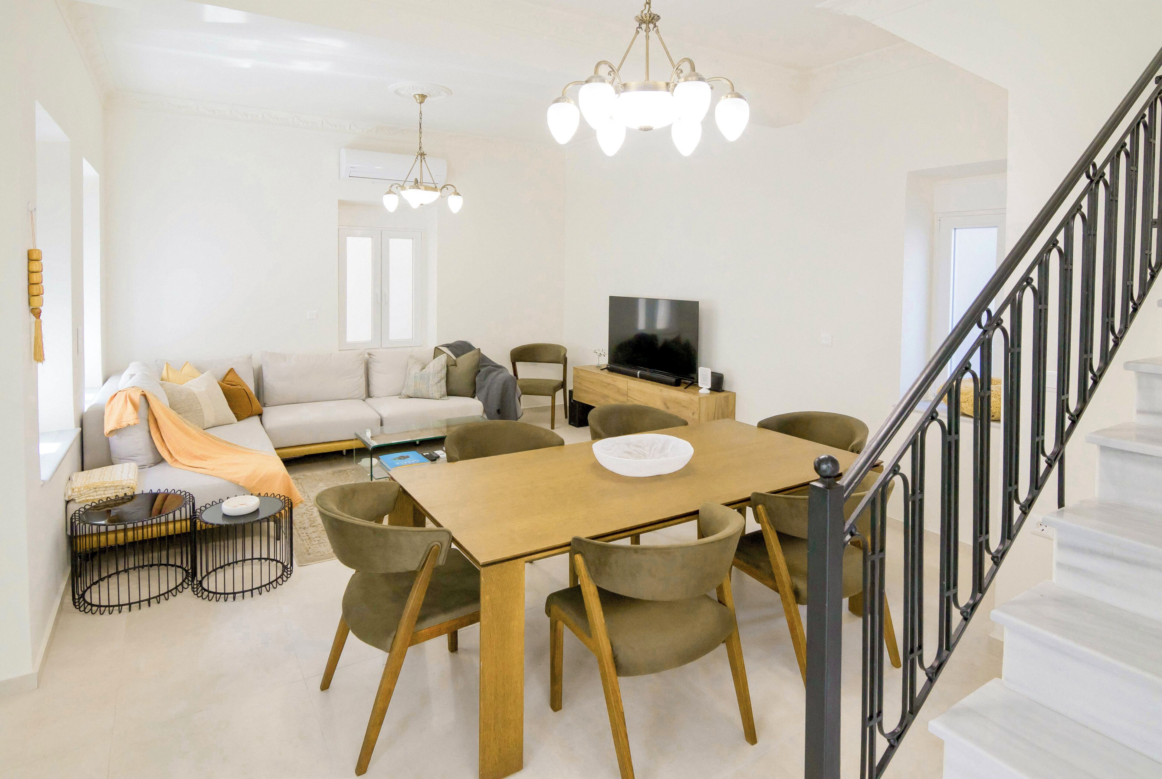 A modern living room with a sofa, TV, dining table, and chairs.