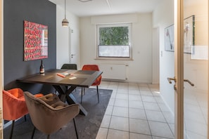 Ein stilvoller Essbereich mit Tisch, Stühlen, einer Weinflasche und Kunstwerken an den Wänden.