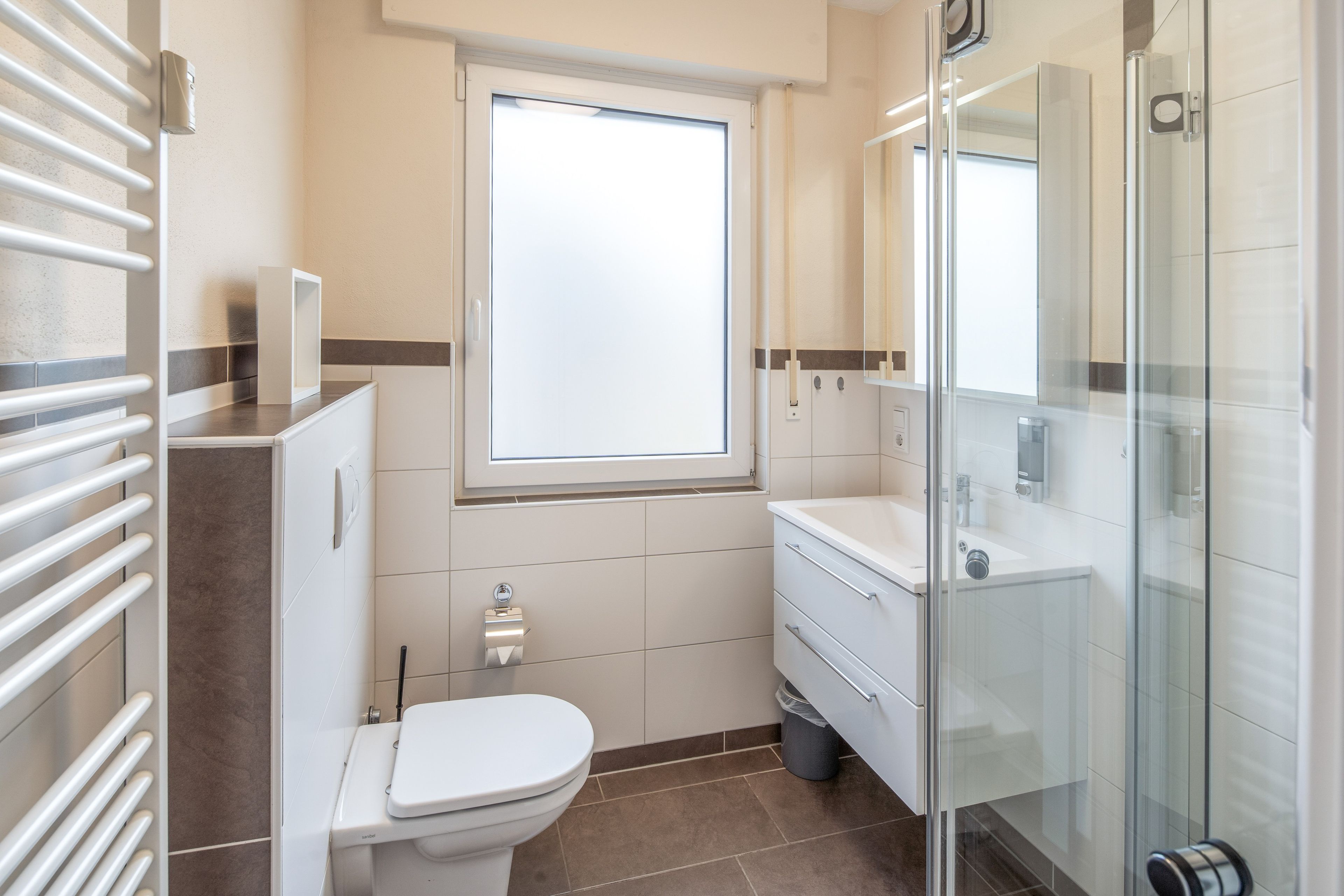 Et moderne badeværelse med toilet, håndvask og brusebad.