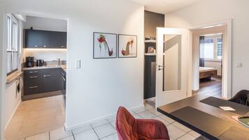 A modern kitchen with dark cabinets, a coffee machine, and a dining area with a red chair and a table.
