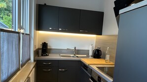 Una cocina moderna con armarios oscuros, un lavamanos de acero inoxidable y un horno empotrado.