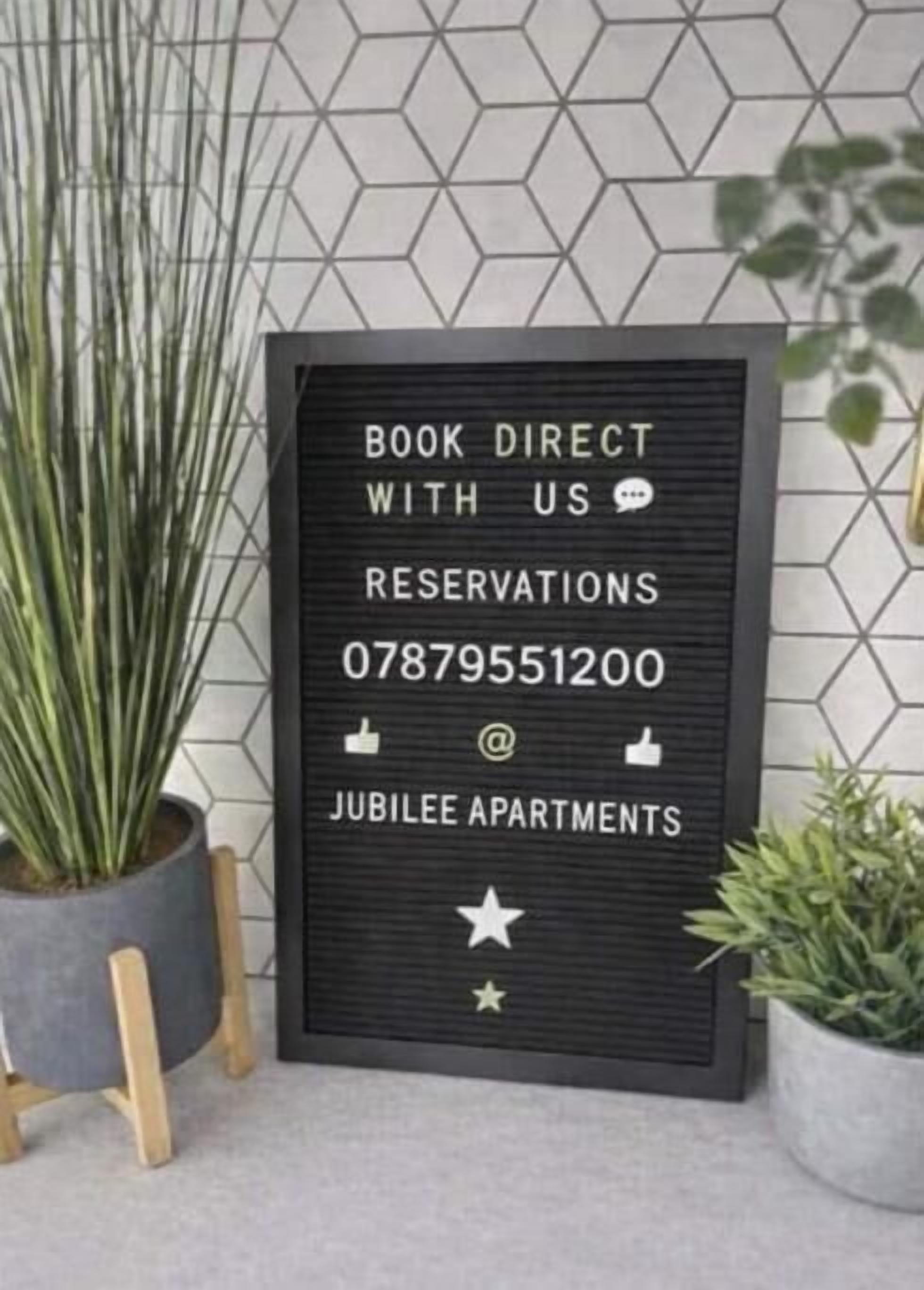 A framed sign with booking information for Jubilee Apartments.