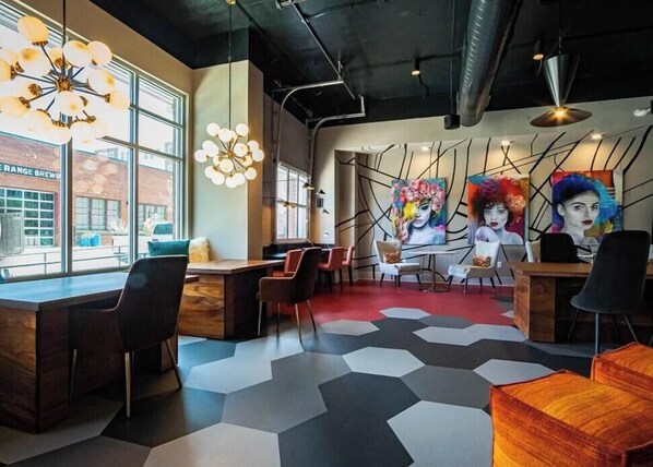 Un intérieur moderne avec un sol à motifs hexagonaux, des meubles en bois et des œuvres d’art abstraites accrochées aux murs.