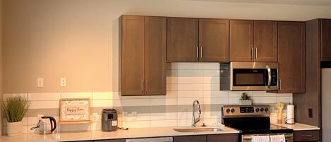 Una cocina moderna con armarios de madera, electrodomésticos de acero inoxidable y piso de madera.