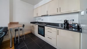 Een moderne keuken met een eethoek, inclusief kasten, een fornuis en een klein tafeltje met stoelen.