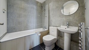 Een badkamer met een bad, toilet, wastafel en een spiegel.