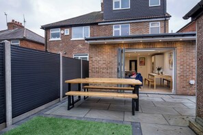 A residential property with a patio, a wooden table, and a brick house.