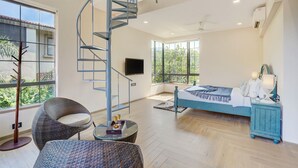 A modern bedroom with a spiral staircase, a bed, a TV, and large windows. - ELIVAAS Villa 39 Serene 6BHK with Pool (Lonavala)