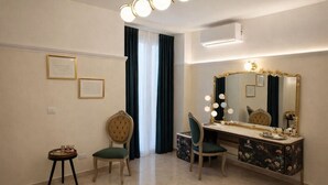 Une pièce comprenant une coiffeuse, deux chaises, une petite table et des certificats encadrés accrochés au mur.