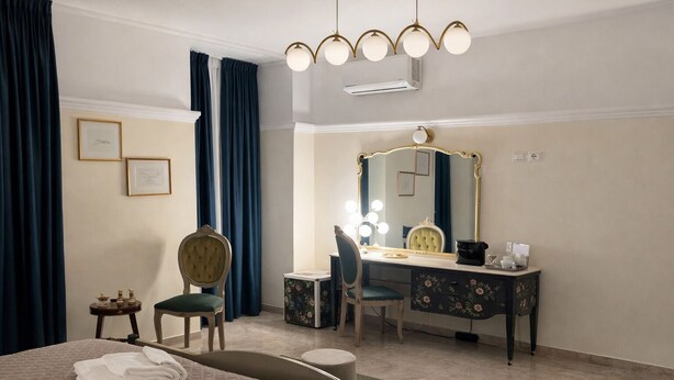Une chambre d’hôtel comprenant un lit, une coiffeuse avec un miroir, une chaise, un bureau et une petite table avec des articles de toilette.
